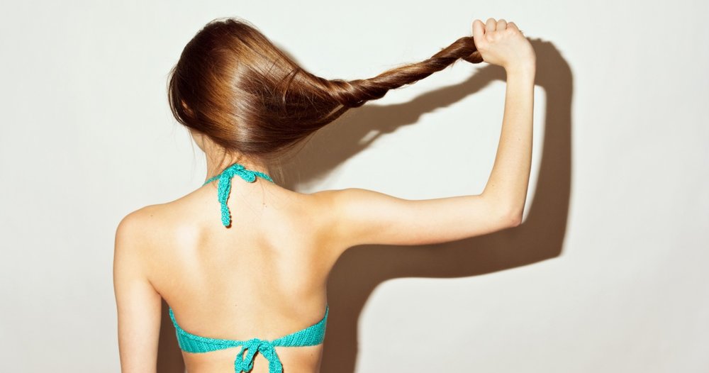 Rear view of young woman in bikini top holding her hair
